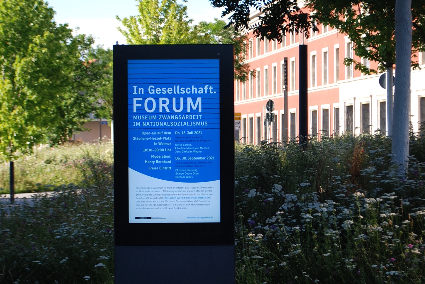 Zu sehen ist das Plakat für das Forum "In Gesellschaft", welches in einem gläserenen Werbeschaukasten in weimar ausgestellt wird.