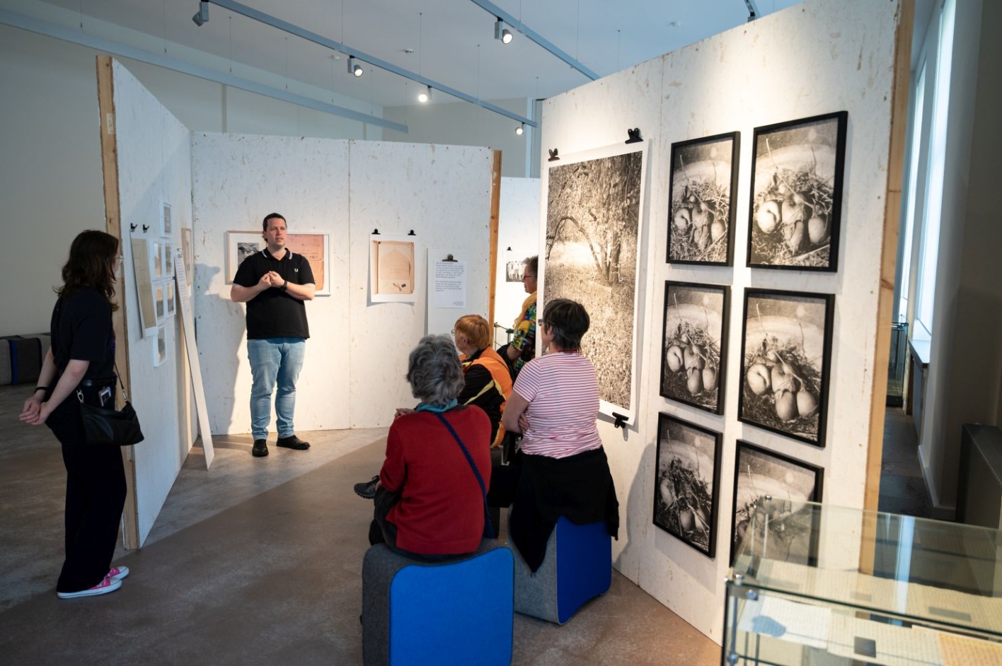 Stefan Weger explains crime scene sketches in the exhibition. A group of people sits in front of him.