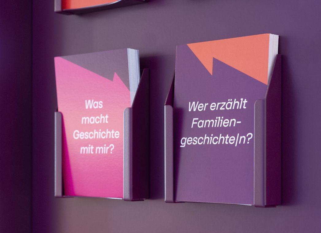 Ansicht von Postkarten an einer Wand mit aufegdruckten Fragen
