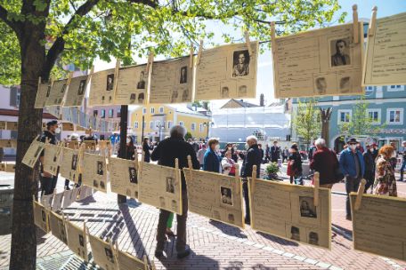 Fotografie der Gedenkveranstaltung auf Schrannenplatz in Erding, im Vordergrund Installation der Arbeitskarten, im Hintergrund Besucher:innen der Veranstaltung