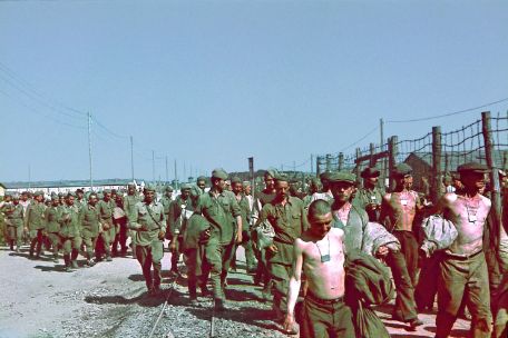 Das Foto zeigt eine Vielzahl von Männern, die mehrheitlich Militäruniformen tragen. Die Männer laufen dem/der Zuschauenden entgegen.