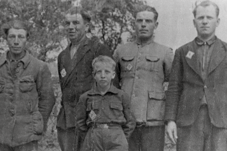 Gruppe polnischer Zwangsarbeiter, gekennzeichnet mit "P"-Abzeichen. Im Vordergrund steht ein kleiner Junge.