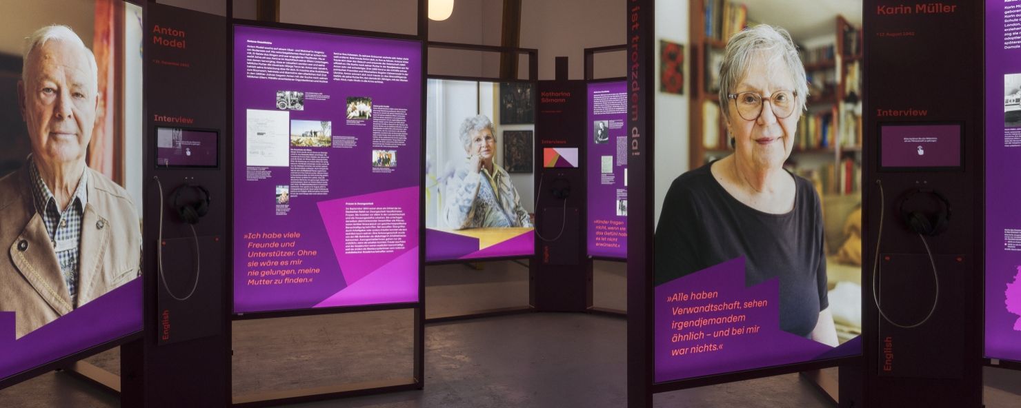 Ausstellungsansicht mit großen Portraitfotos und Informationstafeln mit Text