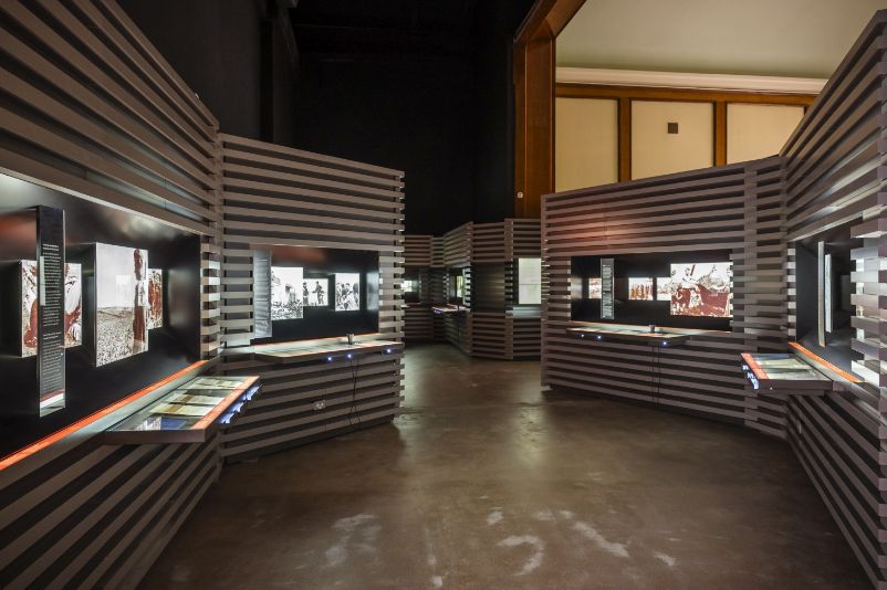 You can see a man looking at the text panels in front of one of the exhibition boxes. Enlarged photographs on the subject of forced labour can be seen in the exhibition boxes.